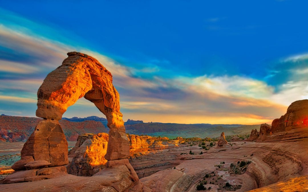 Delicate Arch in Utah with clouds and a clear blue sky.